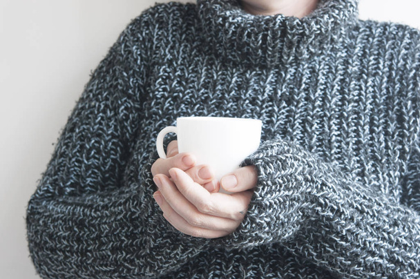 Femme tenant une tasse de café chaud sur un mur blanc, photo rapprochée de
 - Photo, image