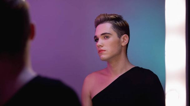 Genderqueer with half-face makeup looking in mirror, non-binary identity concept - Photo, image