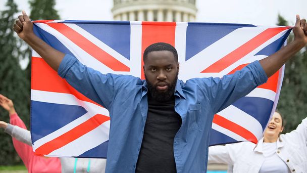 Angry black man raising Great Britain flag, brexit protest, migration crisis - Photo, Image