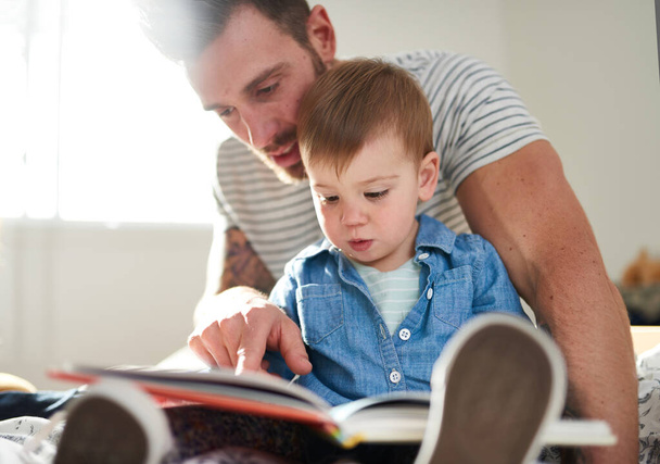 Imádnivaló, fiatal kisbaba, aki kézzel tanul könyvet olvasni. - Fotó, kép