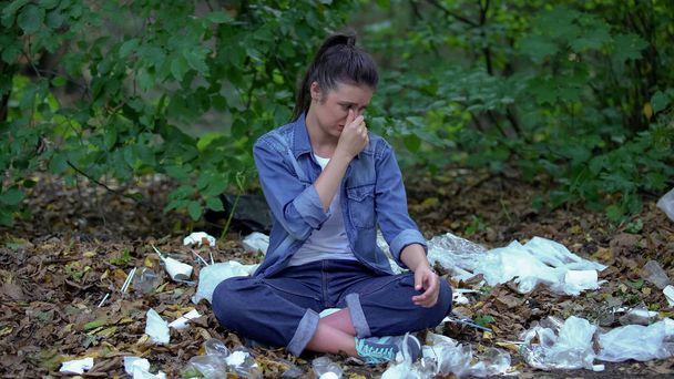 Relaxing woman lotus pose covering nose suffering bad garbage smell, pollution - 写真・画像
