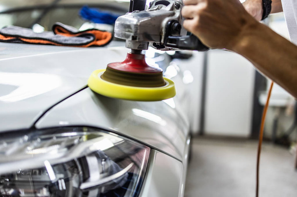 Car detailing - Hands with orbital polisher in auto repair shop. Selective focus. - Φωτογραφία, εικόνα