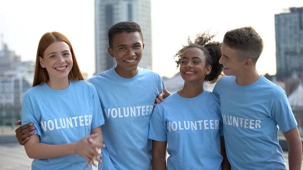 Smiling teen group in volunteer t-shirts looking camera, help, social program - Φωτογραφία, εικόνα