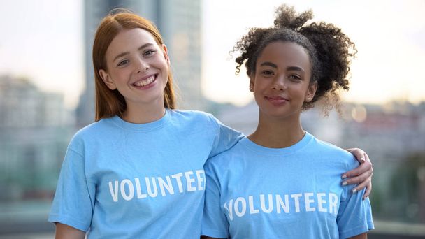 Two female volunteers smiling on camera, high school charity program, altruism - Фото, зображення