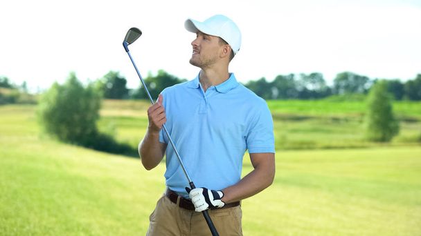 Joyful golf player holding club and smiling, sport equipment, luxury hobby - Foto, Imagen