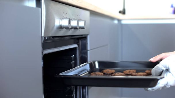 Mulher colocando biscoitos de chocolate no forno, receitas de cozimento caseiro, confeção
 - Foto, Imagem