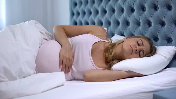 Pregnant woman disturbed with pain in belly, difficult pregnancy, sleep disorder - Zdjęcie, obraz