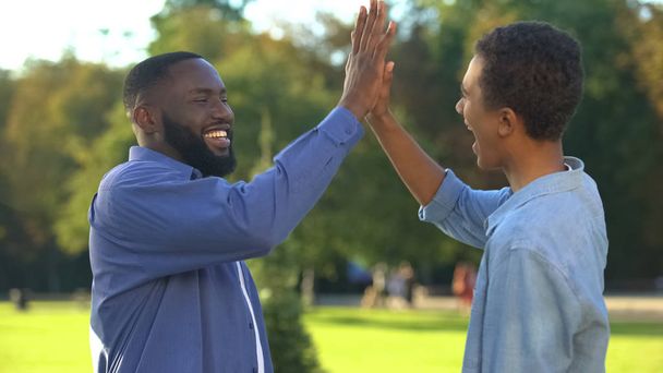 Cheerful black brothers giving high five outdoors, happy family, close relations - Фото, зображення