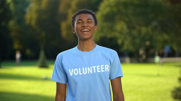 Teen male activist sincerely smiling on camera, eco volunteering project, help - Фото, изображение