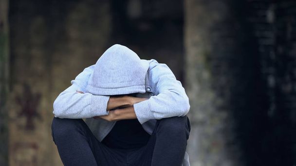 Triste adolescente afro-americano no capuz sentado rua sozinho, pensando em problemas
 - Foto, Imagem