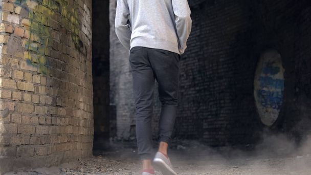Unhappy high school student walking abandoned city building alone, puberty age - Fotó, kép