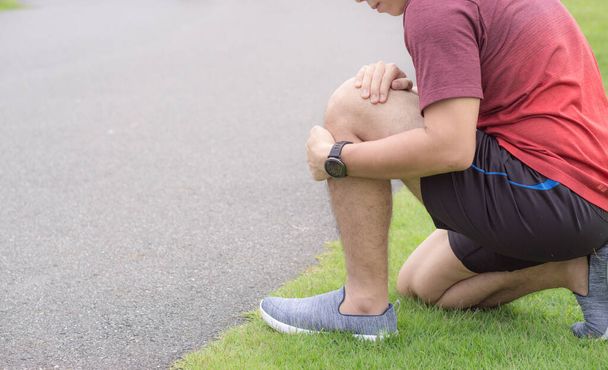 Knieverletzungen. Junger Sportler hält Knie mit den Händen in der Hand - Foto, Bild