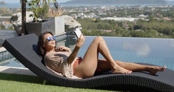 Loungen vrouw nemen selfie aan het zwembad op de top van het hotel - Foto, afbeelding