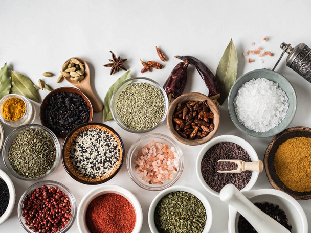 Various dry spices flat lay in small bowls on white wood background. Top view, copy space - Foto, imagen