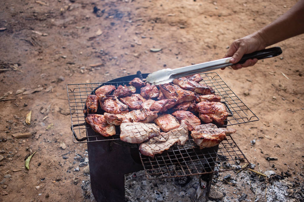 Grilling meat over charcoal stove outdoor - Photo, Image