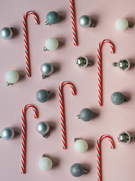 Piso poner la composición de Navidad bastones de caramelo y bolas de Navidad sobre un fondo rosa. Vista superior
 - Foto, imagen