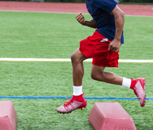 Jogador de futebol atropelando barreiras vermelhas durante a prática de verão
 - Foto, Imagem