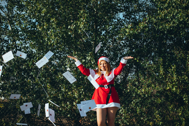 Η μαμά Νόελ πετάει χριστουγεννιάτικες κάρτες στον αέρα στη μέση του δρόμου. - Φωτογραφία, εικόνα