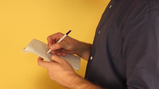 un hombre de pie a media vuelta hace notas en un cuaderno
 - Metraje, vídeo