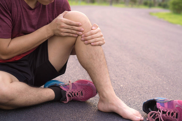 Knieverletzungen. Junger Sportler hält Knie mit den Händen in der Hand - Foto, Bild
