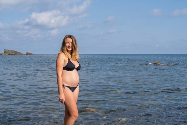 Pregnant woman standing in the sea - 写真・画像
