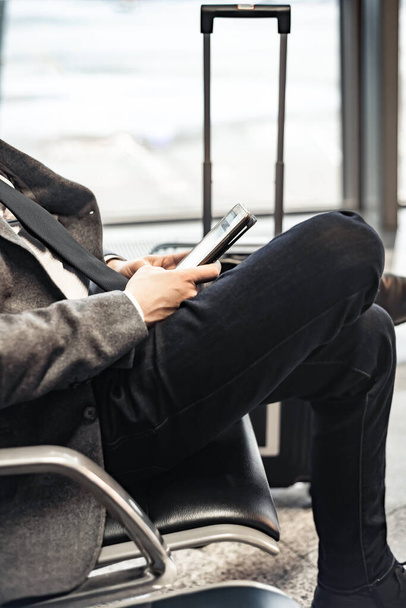 man waiting for his flight at the airport and looking at a mobile phone - Photo, Image