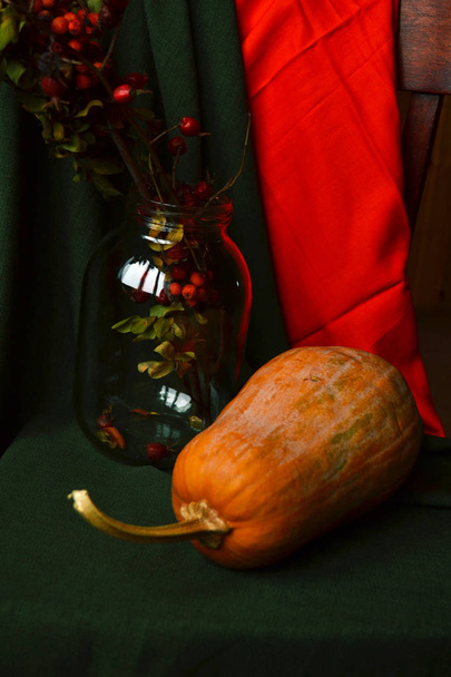 still life pumpkin and glass jar with rowan on green and orange drapery - Foto, Bild