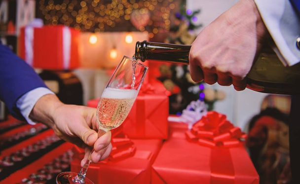 Last minute before new year. Drink champagne or sparkling wine. Celebrate new year with champagne. Cheers concept. Hands pouring champagne into elegant glass christmas decorations background - 写真・画像