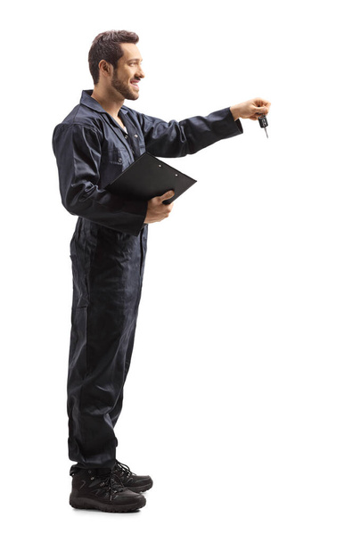 Male worker in overalls holding a clipboard and keys  - Foto, imagen