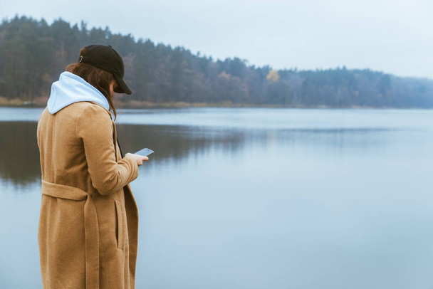 mulher no outono roupa de pé na borda olhando para o lago névoa
 - Foto, Imagem