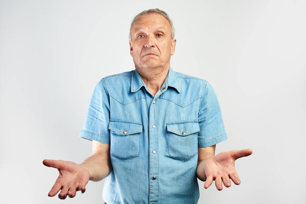 Elderly pensioner throws up his hands in surprise, does not know what to do on white studio background isolated - Photo, image