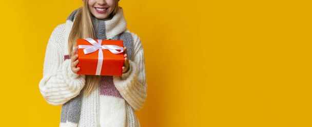 Cropped image of woman in warm sweater holding christmas gift - Fotoğraf, Görsel