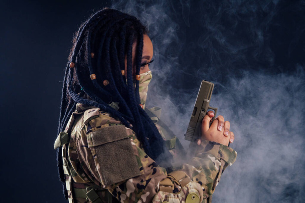 afro american indian army latin soldier in camouflage clothes hair dreadlocks evening makeup in mask on a black background in the studio - Foto, Imagem