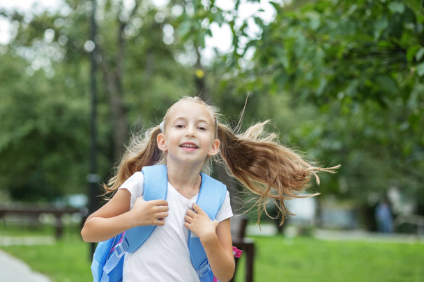 Child girl runs and smiles. Schoolgirl with backpack. The concept of school, study, education, friendship. - Photo, Image