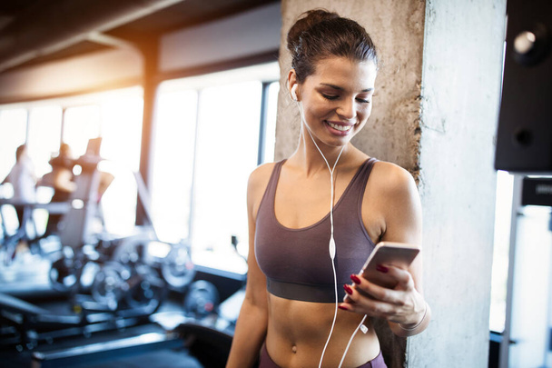 Portrét fit sportovní ženy pomocí mobilu po cvičení v tělocvičně. - Fotografie, Obrázek