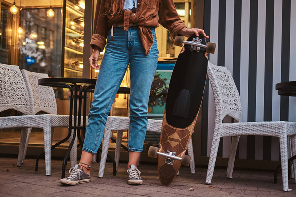 Girl is standing near cafe with longboard - Photo, Image