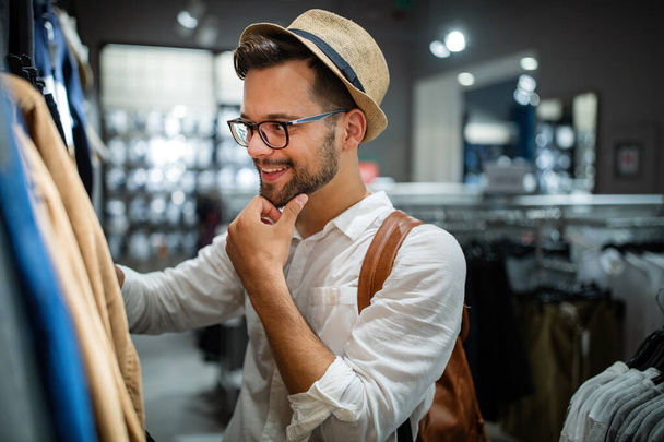 Portrait of a handsome young man shopping for clothes at shop - Fotó, kép