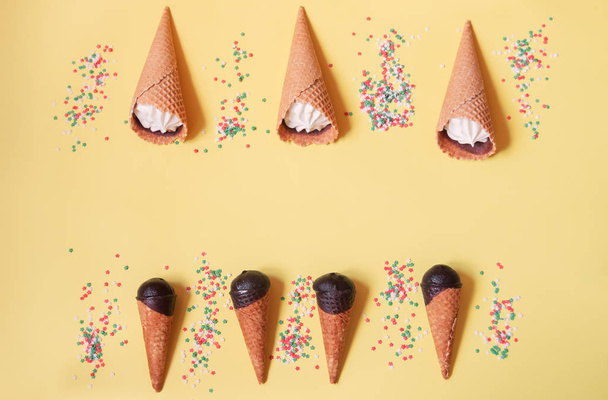 Vanilla ice cream cones and sugar sprinkle stars on yellow background.  - Foto, afbeelding