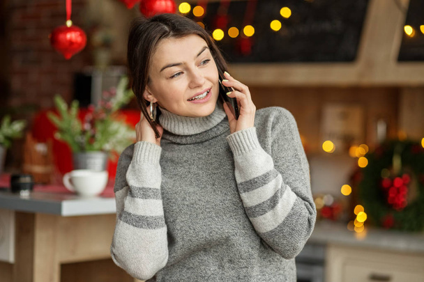 Mooie vrouw spreekt op een mobiele telefoon. Concept winter, levensstijl, Kerstmis en Nieuwjaar. - Foto, afbeelding