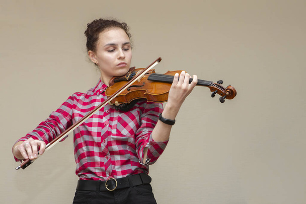 A photo of a young gir playing violin. Young violinist prepares for lesson. - 写真・画像