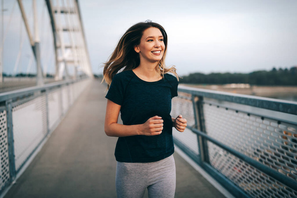 Beautiful fit happy jogger woman crossing bridge - Foto, Imagem