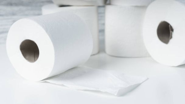 Kupa papieru toaletowego bułki na białym stole na tle niebieskiej ściany tekstury. Produkty higieniczne - Zdjęcie, obraz