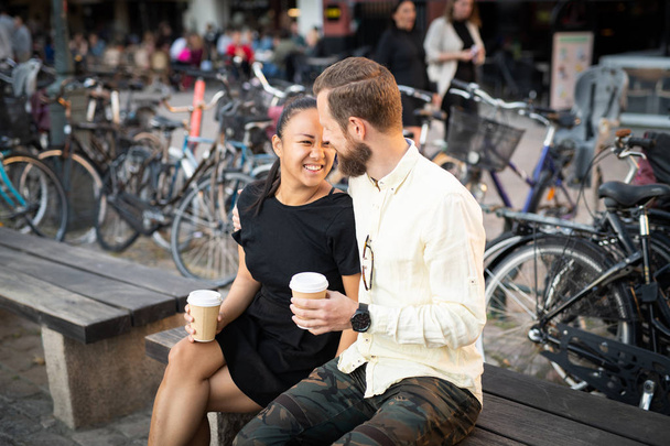 Feliz pareja interracial en el banco al aire libre
 - Foto, imagen