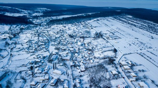 aerial view village among the fields and forests in winter. winter landscape snow covered field and trees in countryside. - Foto, Imagen