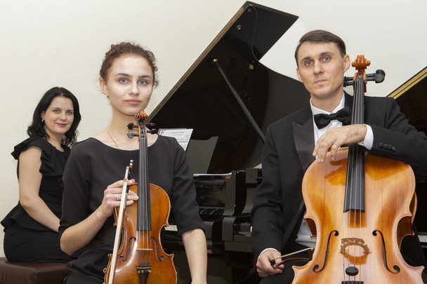 Family music trio. A young violinist and cellist play, the pianist accompanies them. - Foto, Imagem