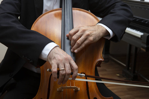 Unrecognizable cellist playing the cello. In the hands of the cellist bow. - Φωτογραφία, εικόνα