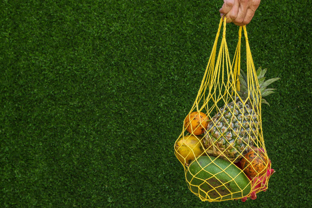 Owoce tropikalne: mango, papaja, ananas, smok i marakuja w żółtym torbie na zakupy na zielonym tle, orientacja pozioma, przestrzeń do kopiowania - Zdjęcie, obraz