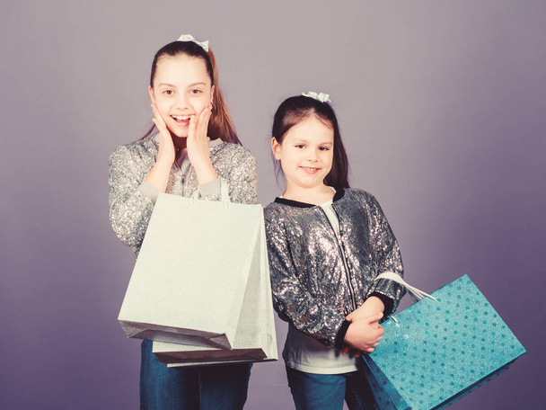 Girls sisters friends with shopping bags violet background. Shopping and purchase. Black friday. Sale and discount. Shopping day. Children bunch packages. Kids fashion. Discover something new - Фото, зображення