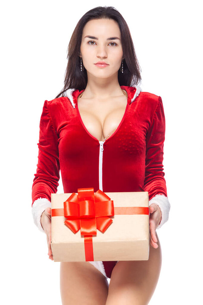 Christmas. Sports fitness girl in red sexy Santa Claus costume holding a gift box tied with a red ribbon with a bow. Isolated on white background. - 写真・画像