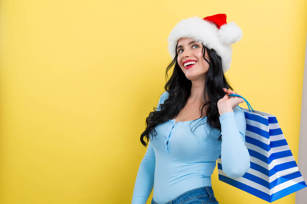 Young woman with santa hat holding a shopping bag - Foto, imagen